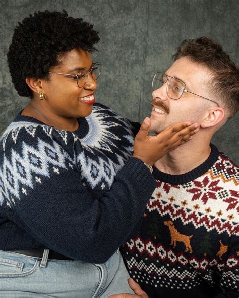 A Man And Woman Are Laughing Together In Front Of A Gray Wall One Is