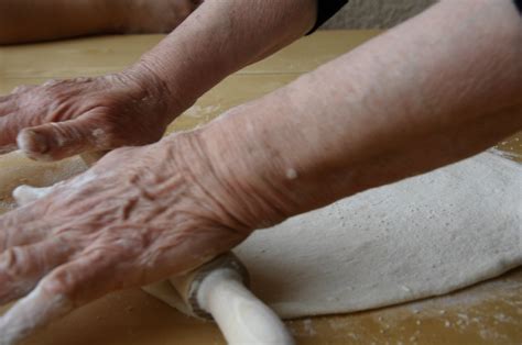 An Older Person Kneading Dough On Top Of A Table