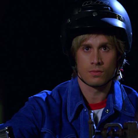 A Man Wearing A Blue Jacket And Helmet Sitting In Front Of A Black