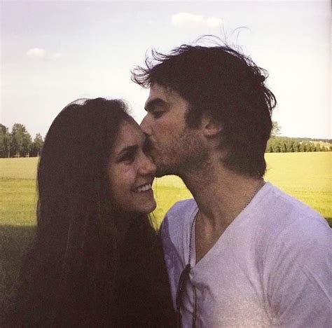 A Man And Woman Are Kissing In Front Of A Field