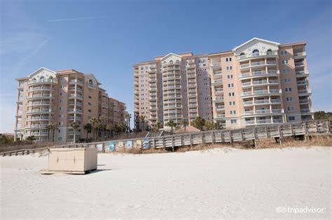 Two Buildings On The Beach With Sand In Front