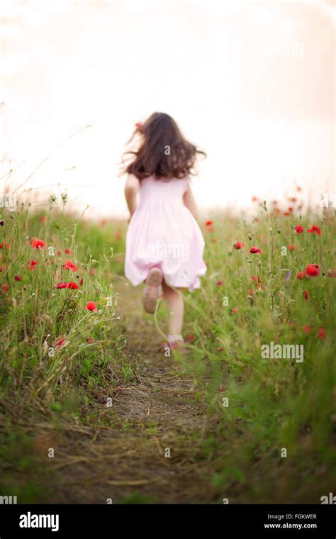 Little girl running away in a field of poppies Stock Photo - Alamy