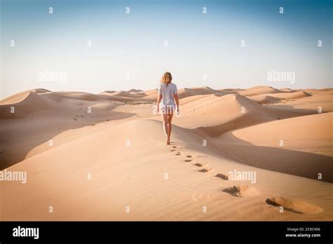 Blonde Female Caucasian Traveler Leaving Footprints In Sand Dunes When