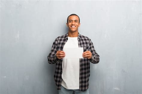 El Hombre Afroamericano Joven Con La Camisa A Cuadros Que Lleva A Cabo