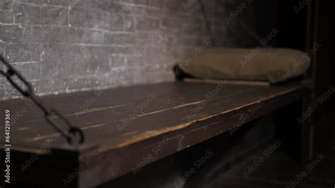 A Close Up Of A Wooden Bed Hanging On Chains A Shelf With A Pillow In An Old Prison Cell A