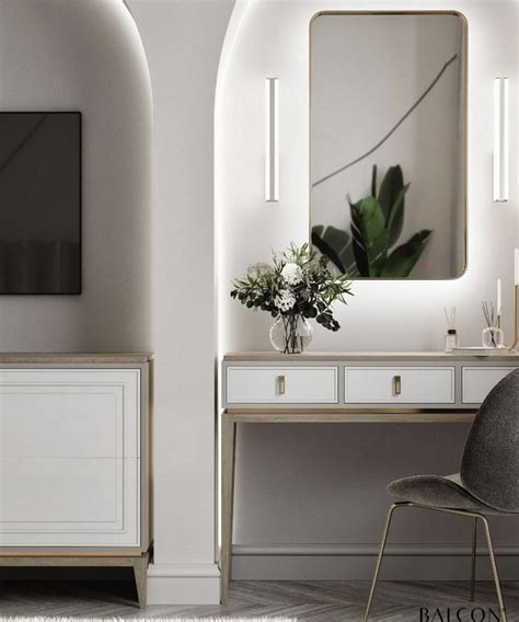 A White Desk With A Mirror And Vase On It Next To A Wall Mounted Television