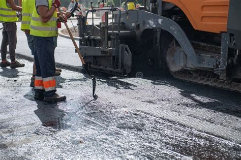 Workers Operating Asphalt Paver Machine During Road Construction And