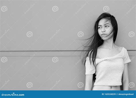 Young Beautiful Asian Teenage Girl Thinking While Leaning Against