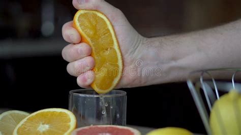 A Man Squeezes Orange Juice With Citrus Juicer Close Up Of Hands