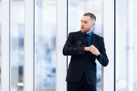 Portrait Of Handsome Man Standing In A Suit And Tie In Front Of Glass