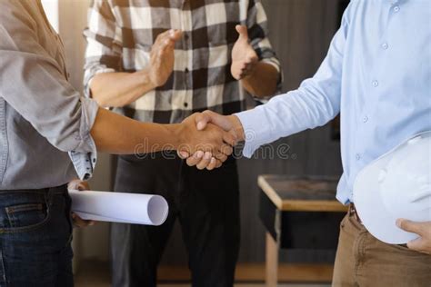 Construction Worker And Contractor Client Shaking Hands With Team