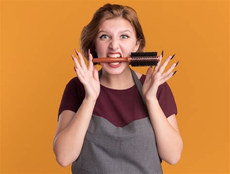 Peluquería de mujer hermosa joven en delantal con cepillo de pelo en la