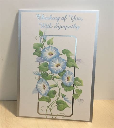 A Greeting Card With Blue Flowers And Green Leaves On The Front