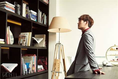 A Man Sitting At A Desk In Front Of A Book Shelf With Books On It