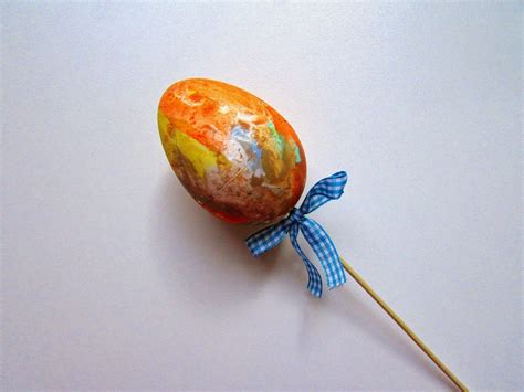 An Egg Shaped Lollipop With A Blue Bow On Its End Sitting On A White