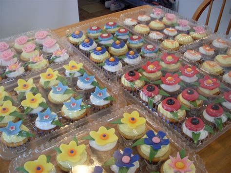 Cupcakes Are Arranged On Plastic Trays With Flowers And Leaves In The