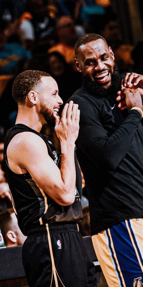 Two Men Standing Next To Each Other On A Basketball Court