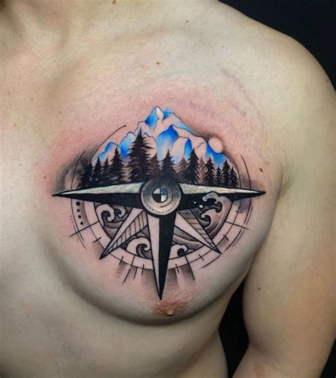 a man's chest with a compass tattoo on it and mountains in the background