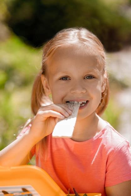 Premium Photo Cute Blonde Girl Having A Snack And Looking Contented