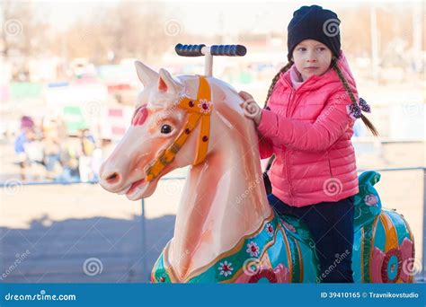 Little Happy Girl Riding On Carousel At An Amusement Park Stock Image