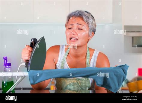 Desperate And Stressed Middle Aged Asian Woman Ironing In Stress At