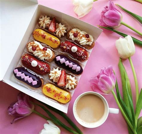 A Box Filled With Different Types Of Pastries Next To Flowers And A Cup