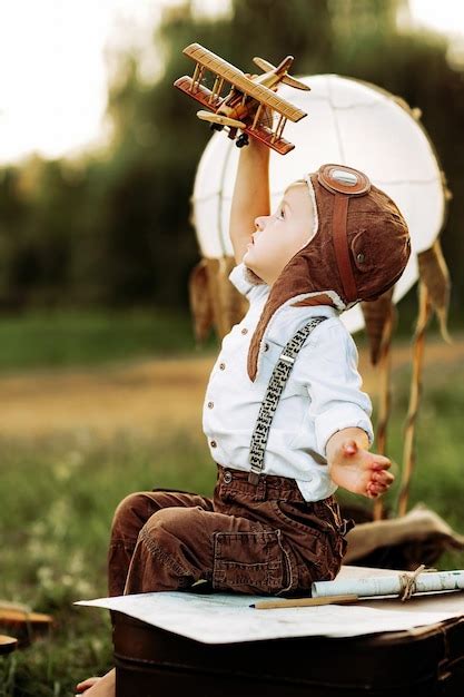 Lindo niño piloto con sombrero de aviador vintage sentado y jugando con