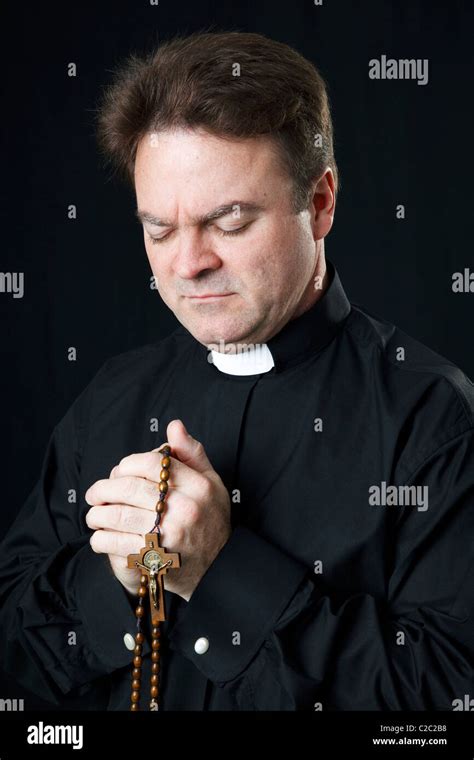 Catholic priest praying with his rosary beads Stock Photo - Alamy