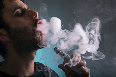 Young Man Vape Electronic Cigarette Cloud By Using A Mod Smoke Tricks