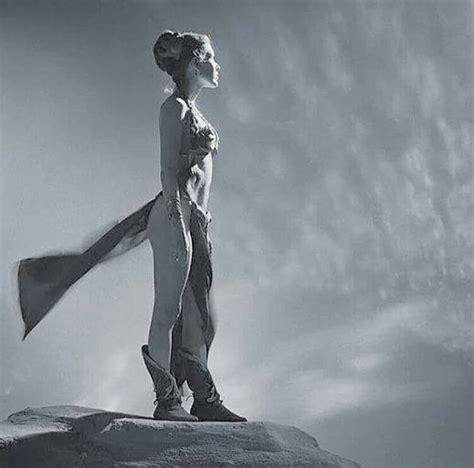 A Black And White Photo Of A Woman Standing On Top Of A Rock