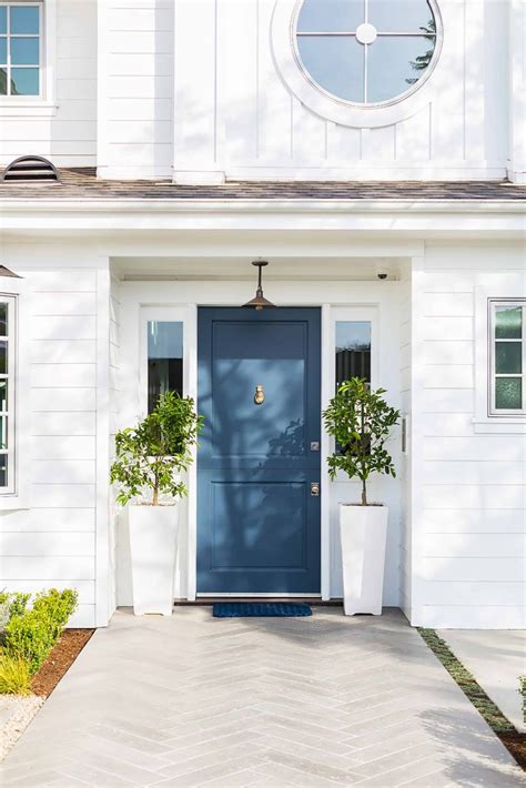 A White House With Blue Front Door And Potted Plants