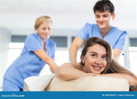 Two Masseurs Man And Woman Are Doing Back Massage Of Young Woman