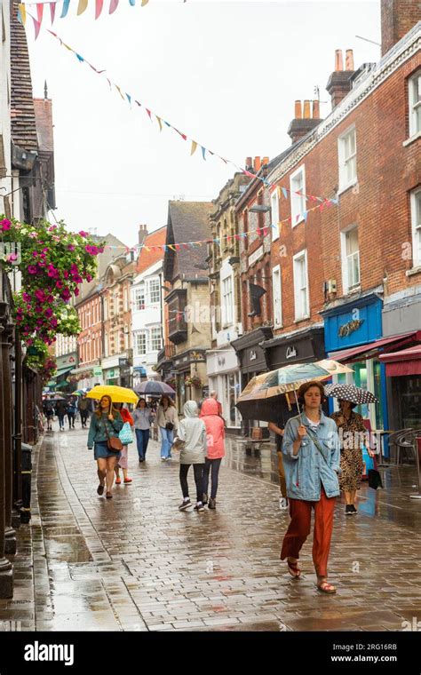 People Walking And Shopping In The Rain Under Umbrellas In The High