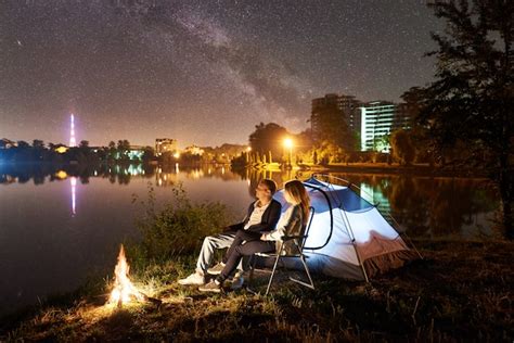 Premium Photo | Night camping on lake shore. man and woman sitting on ...