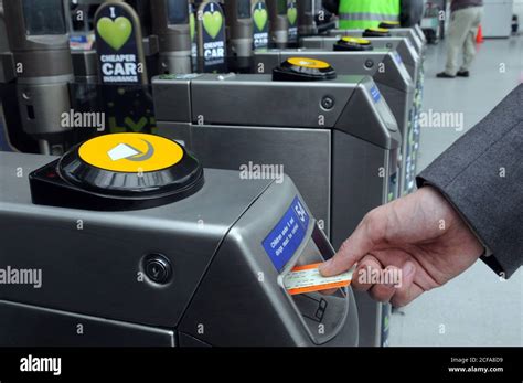 Hand Putting Train Ticket Into A Tfl Stations Ticket Barrier In Greater