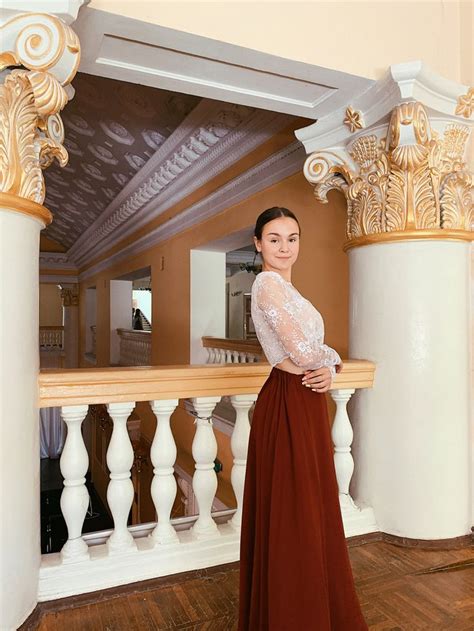 A Woman In A Long Red Dress Standing On A Wooden Floor Next To White