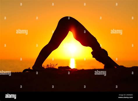 Silueta de una mujer haciendo yoga en la playa fotografías e imágenes