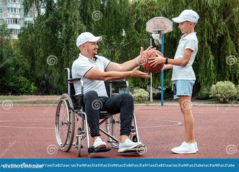 A Disabled Dad Plays With His Son On The Street Wheelchair Concept