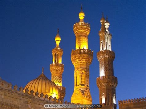 two tall buildings lit up at night with lights on them and one in the foreground