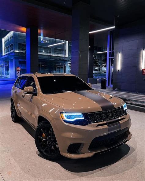 A Tan Jeep Is Parked In Front Of A Large Building With Blue Lights On It