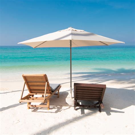 Two Lounge Chairs Under An Umbrella On The Beach