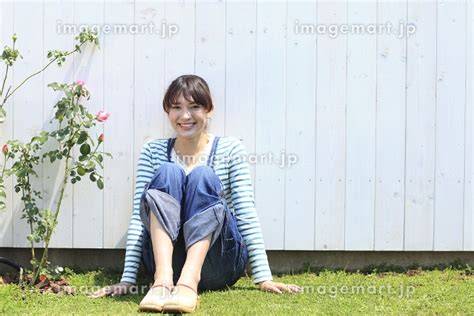 バラの咲く庭に座る女性の写真素材 21104440 イメージマート