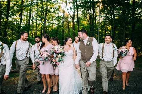 A Bride And Groom Walking With Their Bridal Party In The Woods At This