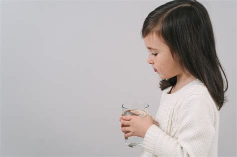 El Ni O Bebe Agua De Un Vaso Una Ni A De Cabello Oscuro Sostiene Un