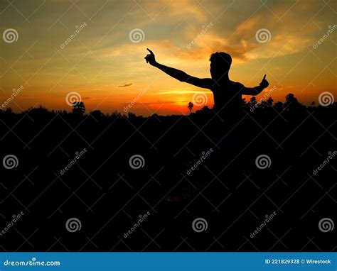 Silhouette Of A Person With His Arm Wide Open Captured At Sunset Stock