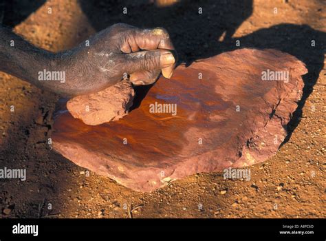 Aboriginal Man Rubbing Red Ochre On Rock To Produce Red Powder For