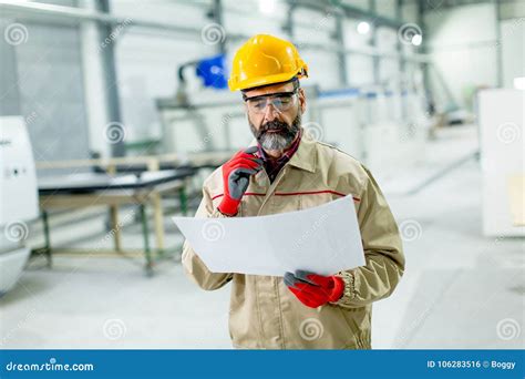 Handsome Mature Engineer Looking At Plan In The Factory Stock Photo