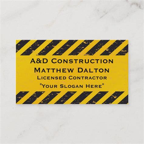 a yellow and black construction business card on a white marble surface ...