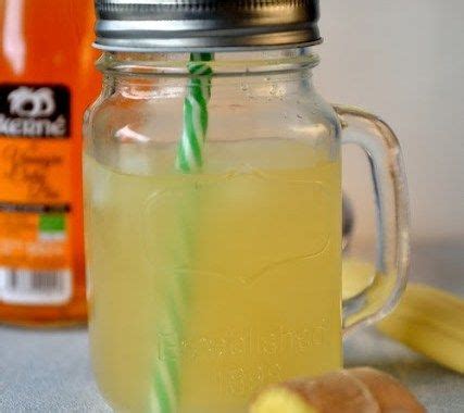 A Mason Jar Filled With Lemonade And Two Green Straws Next To Some