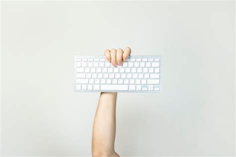 Premium Photo | Male hand holds a keyboard on a light isolated